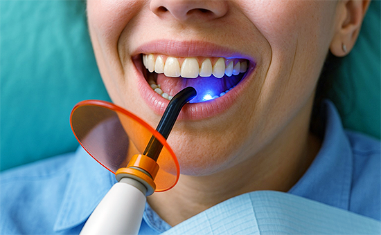 Zahnarzt untersucht lächelnde Patientin mit moderner Zahnlampe – Allgemeine Zahnheilkunde in der ACC Zahnklinik Basel