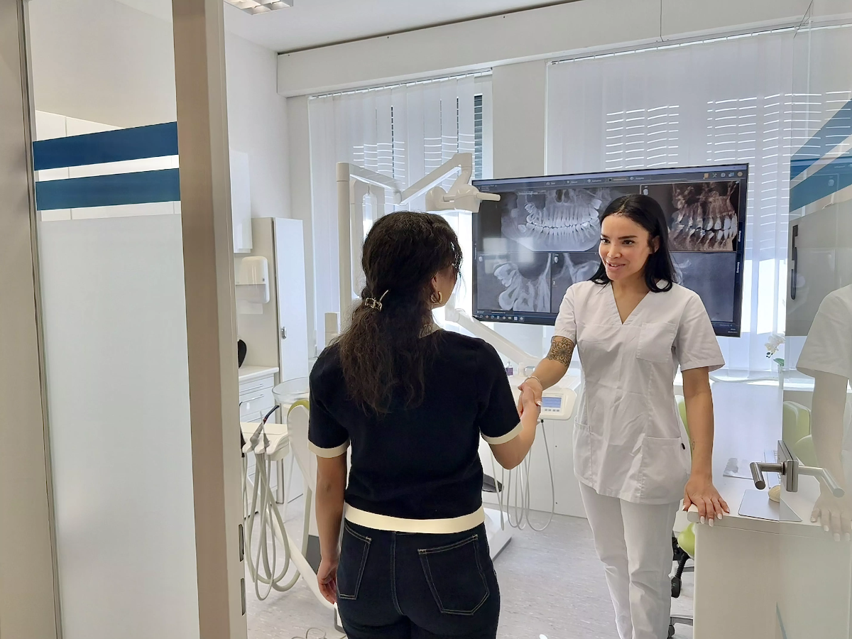 Praxisassistentin begrüsst Patientin freundlich im Behandlungszimmer – Rundgang durch die ACC Zahnklinik Basel