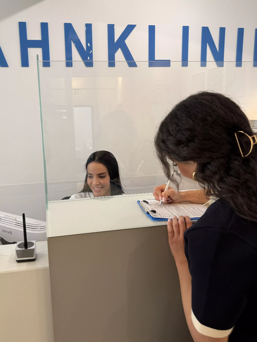 Patientin füllt Formular am Empfang der ACC Zahnklinik Basel aus – effizienter Praxisablauf beim typischen Praxisbesuch